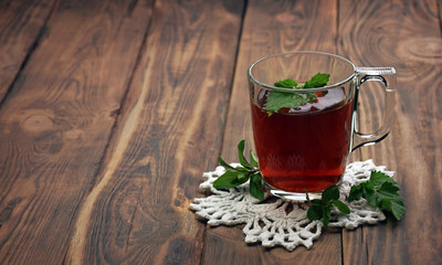 A fragrant herbal tea with mint leaves, lemon balm, raspberries and currants. Close-up. A cup of herbal tea on a wooden background.