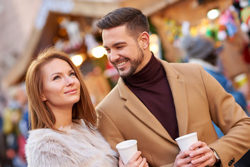 A beautiful young couple drinking mulled wine in a christmas market.