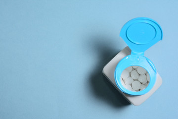 open plastic jar with tablets on a blue background, top view