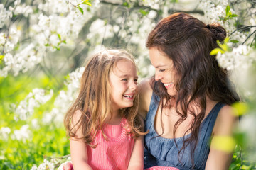 Fototapeta premium Mother and daughter in spring cherry blossom park