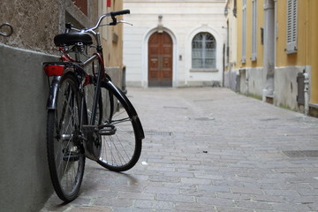 Fototapeta na wymiar bicicletta nera vintage appoggiata al muto città antica