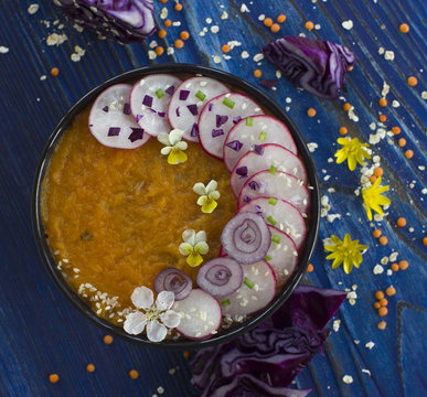Summer bowl of cream soup with vegetables and flowers