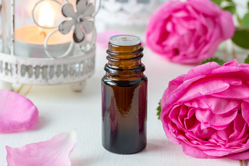 A bottle of essential oil with fresh roses