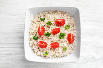 Plate with delicious brown rice and vegetables on table