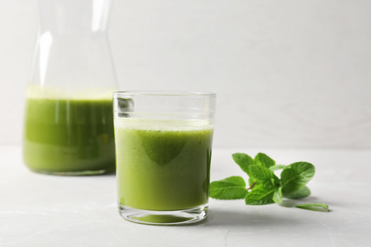 Glassware with delicious detox juice and mint on table
