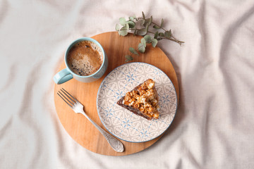 Piece of delicious homemade cake with caramel sauce and cup of coffee on wooden board, top view