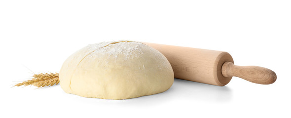 Raw wheat dough, rolling pin and spikes on white background