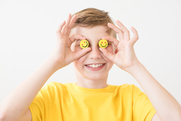Laughing boy holding in his hand a funny yellow smileys instead of eyes