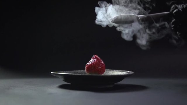 A spoon with liquid nitrogen drops to the strawberry.