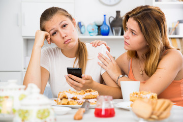 Obraz na płótnie Canvas Female talking with young sad friend with mobile