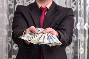 Man in suit showing dollar banknotes, close up