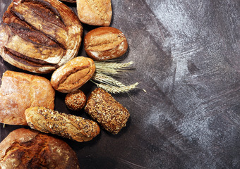 Different kinds of bread and bread rolls on board from above. Kitchen or bakery