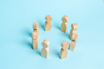 Wooden figures of people stand in a circle and conduct a conversation. The concept of communication and cooperation of workers and social groups. Social networks, collectives and citizens' meeting.