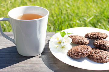 A cup of tea and the biscuits on the wooden table in the early morning. Light breakfast