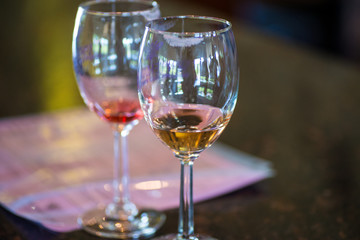 close up two wine glasses at vineyard, tasting reds and whites. bottles in background