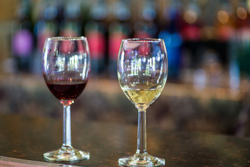 close up two wine glasses at vineyard, tasting reds and whites. bottles in background