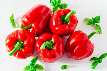 group of red ripe organic bell pepper and fresh basil leaves isolated on white