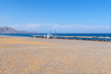 Kalathos beach located near Kalathos village. Pebble and sandy beach with many sun beds with umbrellas. Rhodes island, Greece