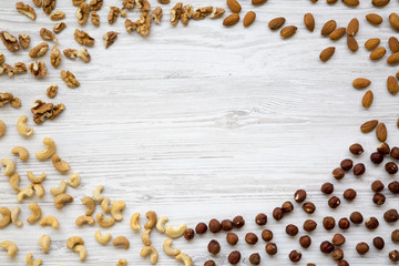 Different nuts on white wooden background. Cashew, hazelnuts, walnuts, almonds. Top view, flat lay. Copy space.
