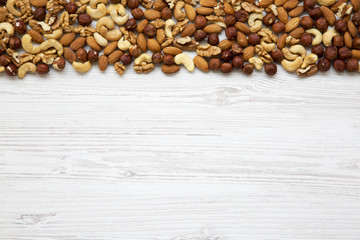 Assorted mixed nuts (cashew, hazelnuts, walnuts, almonds) on white wooden background, top view. From above. Copy space.