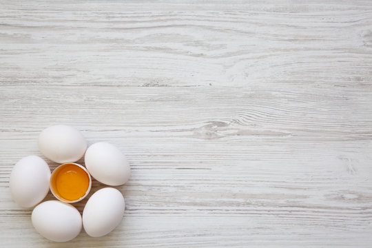 Chicken eggs on white wooden background, top view. Copy space.