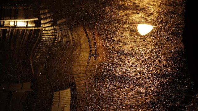  Vision deformada inquietante y surrealista de noche en la ciudad con tormenta de  lluvia en el asfalto y farola que se balancea 

