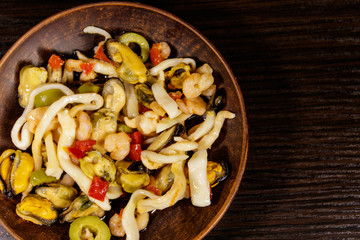 Seafood salad with shrimp, squid and mussels on wooden table