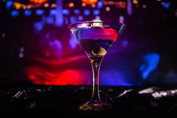 glass with martini with olive inside. Close up view of glass with club drink on dark foggy toned background. Club drink concept