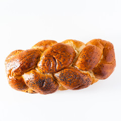 braided bread sprinkled with poppy seeds, isolated on white. copy space