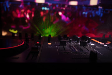 Fototapeta na wymiar In selective focus of Pro dj controller.The DJ console deejay mixing desk at music party in nightclub with colored disco lights.