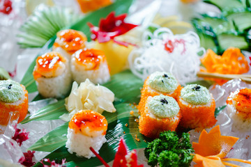 A lot of sushi rolls with different fillings. Shot of cooked classic Japanese food served on ice in a huge wooden bowl. Background image