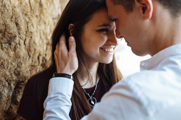 young, happy, loving couple, near the sand wall, on the sea, in the arms, and look at each other, advertising and inserting text