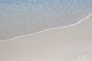 Smooth sea water on sand beach photo background. Soft wave on white beach sand. Tropical seashore idyllic view.