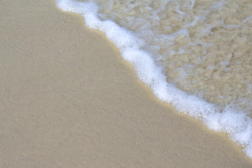 Foamy sea wave on sand beach photo background. Tide on white beach sande. Tropical seashore idyllic view
