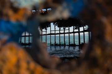 A view of the sea through the hole of a rusty shipwreck