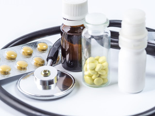stethoscope, yellow pills in a box and bottles on a white background