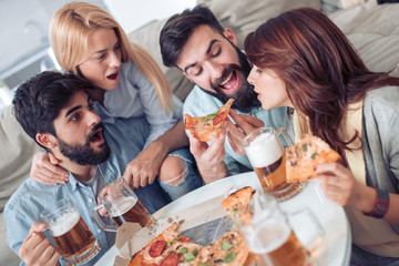 Group of friends taking their slices of pizza