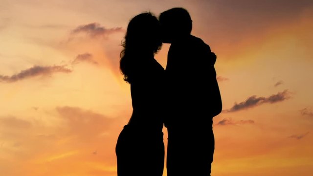 Beautiful romantic couple enjoying amazing sunset, kissing and hugging, closeup