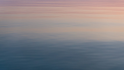 Naklejka na ściany i meble Beautiful sunset reflected in calm mirrored water surface.