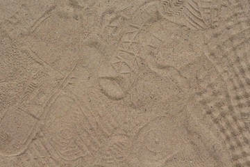 Yellow sand with foot marks photo texture. Shoe sole sand marks. Many tourist shoe protectors background