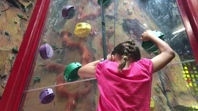 Young girl (age 7) climbing on a climbing wall.