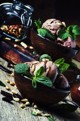 Chocolate ice cream with nuts in bowls on old wooden background, selective focus
