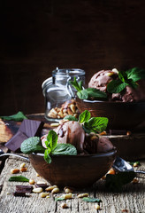 Chocolate ice cream with nuts in bowls on old wooden background, selective focus
