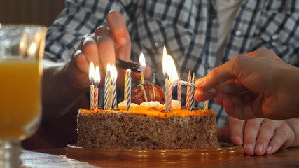 Two hand lighting candles in birthday cake