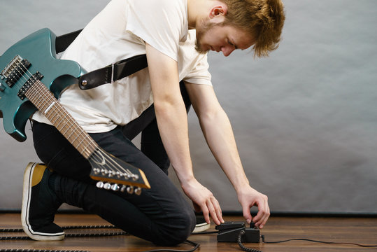 Man adjusting guitar effects pedal
