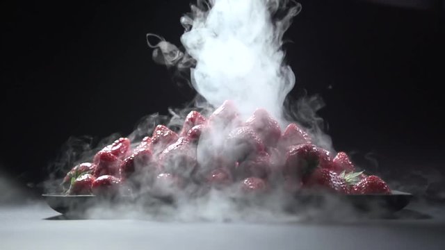 The smoke pours on the plate with the berries slowly.