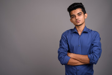 Young Indian businessman against gray background