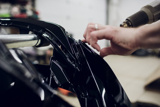 Worker hands installs car paint protection film wrap bumper