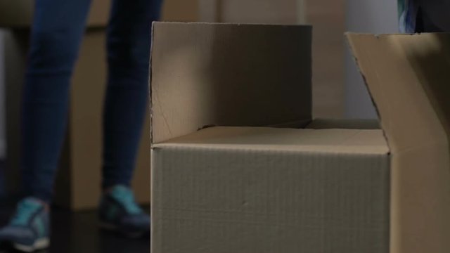 Angry wife waiting until husband gathering stuff into cardboard box, divorce