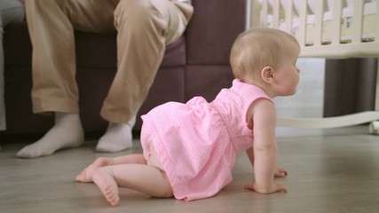 Baby crawling on floor at home. Happy family concept. Cute baby girl crawl in home with parents. Adorable child walking on floor. Toddler walking in home. Sweet childhood
